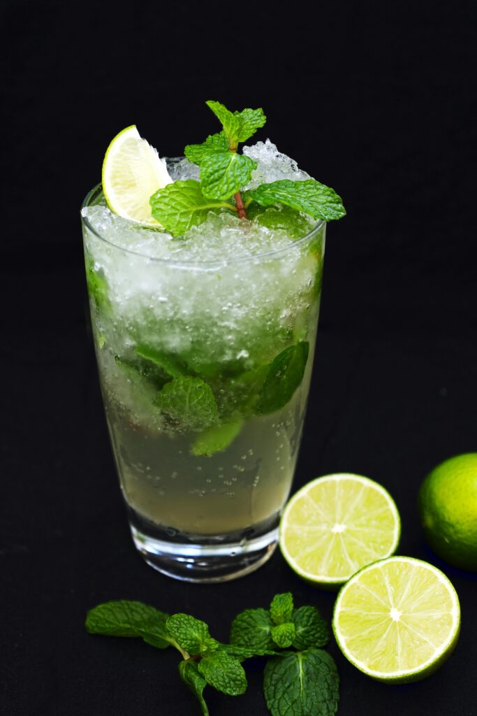 Close-up of a chilled mojito with lime slices and mint against a dark background.